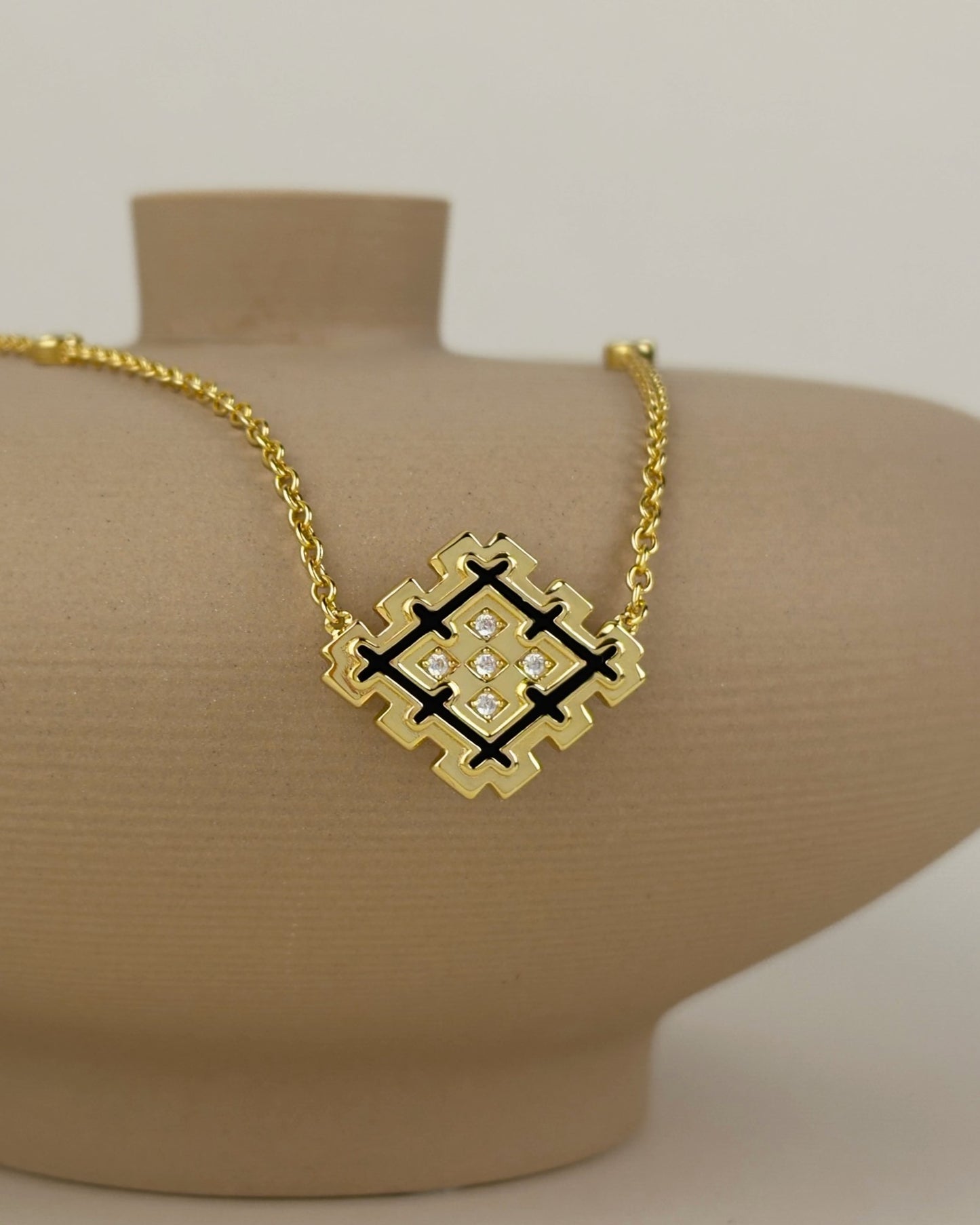 Close-up of the Lion’s Paw black enamel necklace in 18K gold vermeil displayed on a beige jewelry bust.