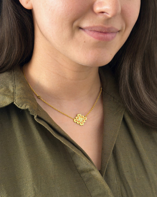 Woman wearing an orange enamel Lion’s Paw necklace in gold vermeil, styled with an olive shirt for a natural lifestyle look.