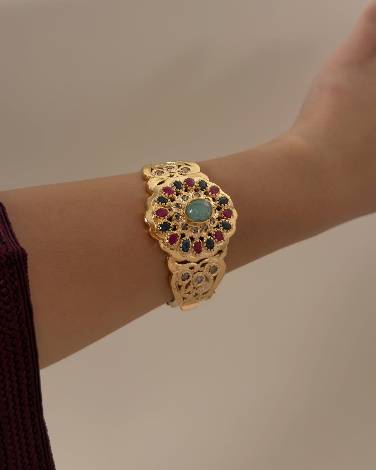 Wider lifestyle view of the multicolour Moroccan bracelet worn on a wrist against a beige background.