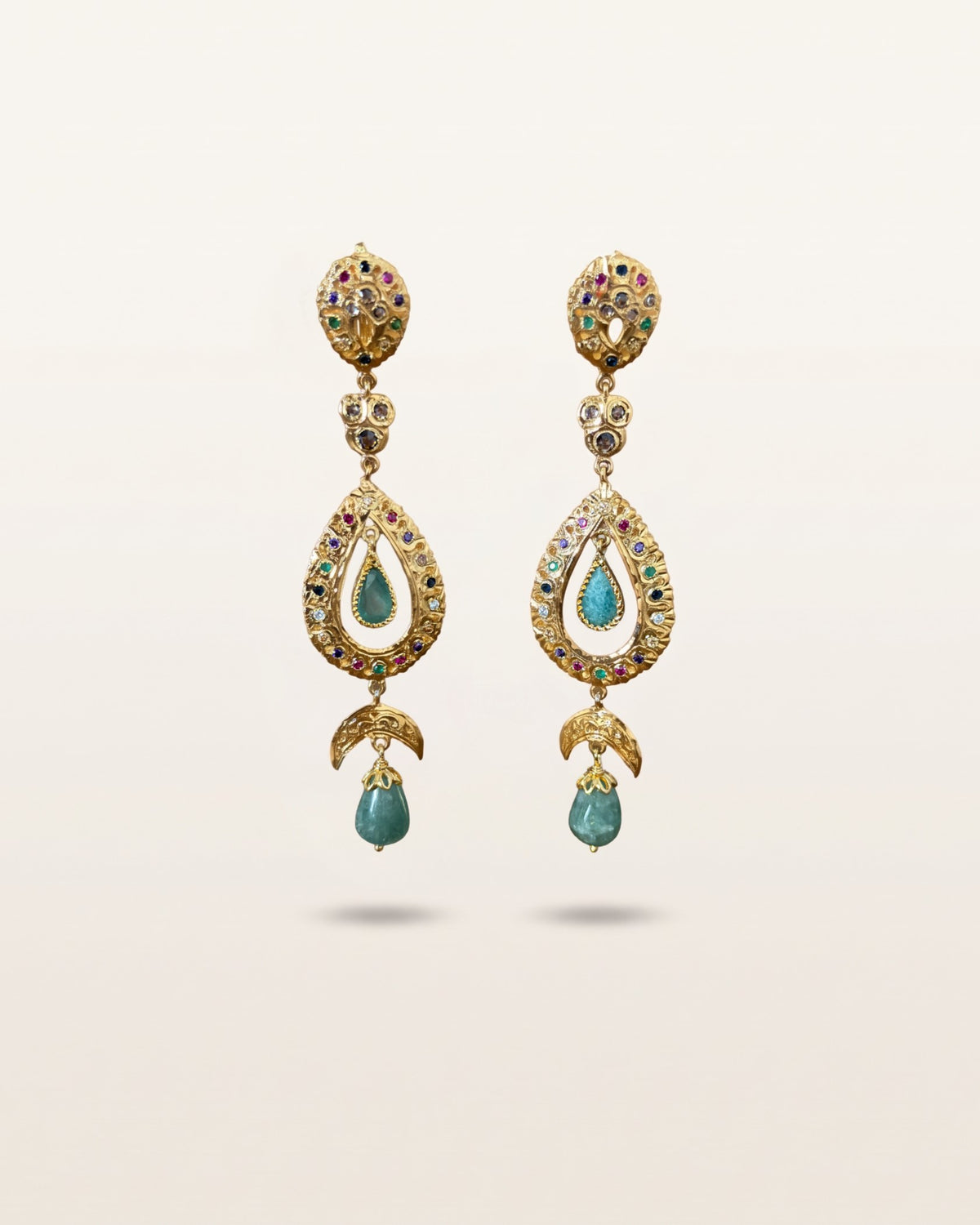 Pair of Moroccan sterling silver drop earrings with gold plating, multicoloured stones and green cabochons on an ivory background.