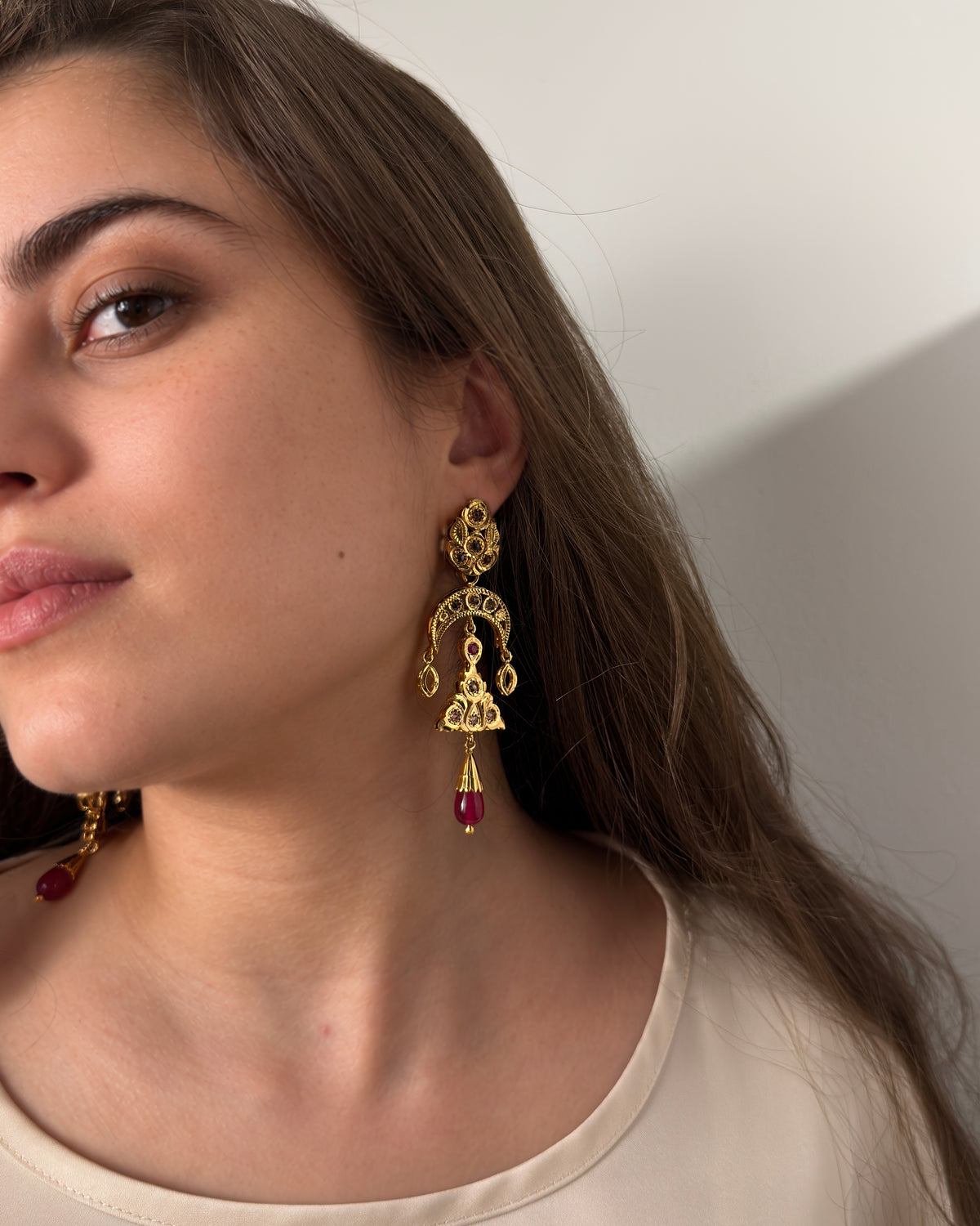 Close-up of handcrafted Moroccan rosette earring with gold details and red cabochon