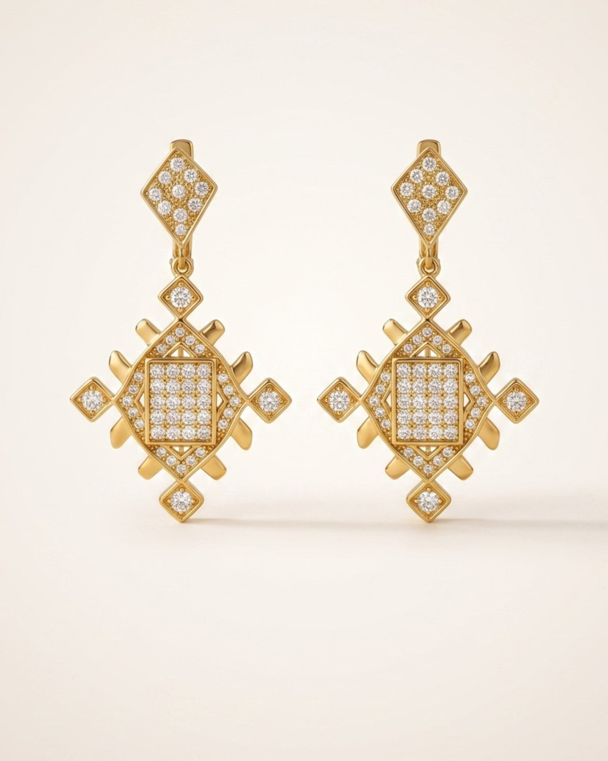 Pair of gold Lion’s Paw statement earrings with sparkling cubic zirconia details displayed on a soft neutral background.