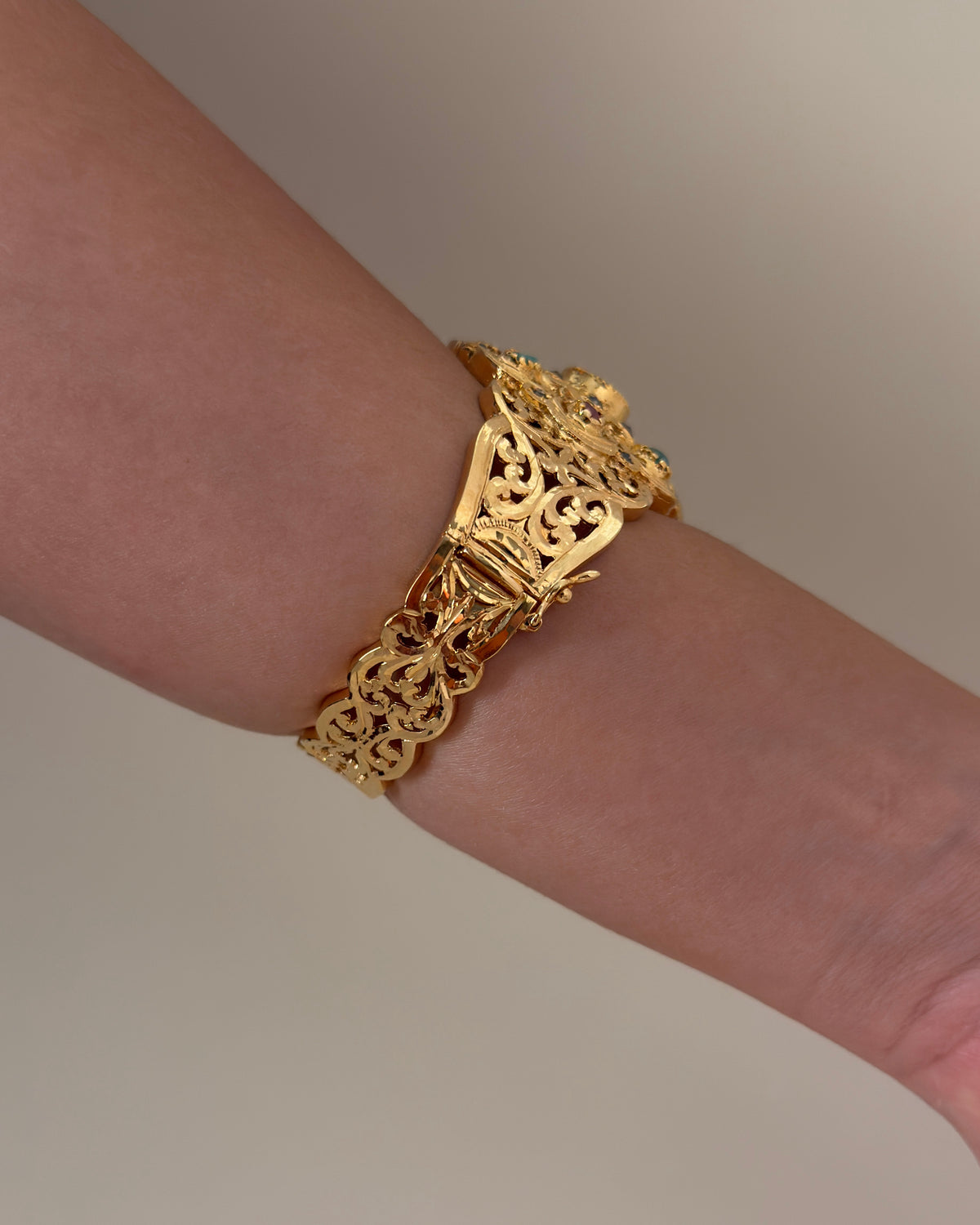 Side view of the bracelet worn on a wrist, showing the gold-plated openwork band and clasp.