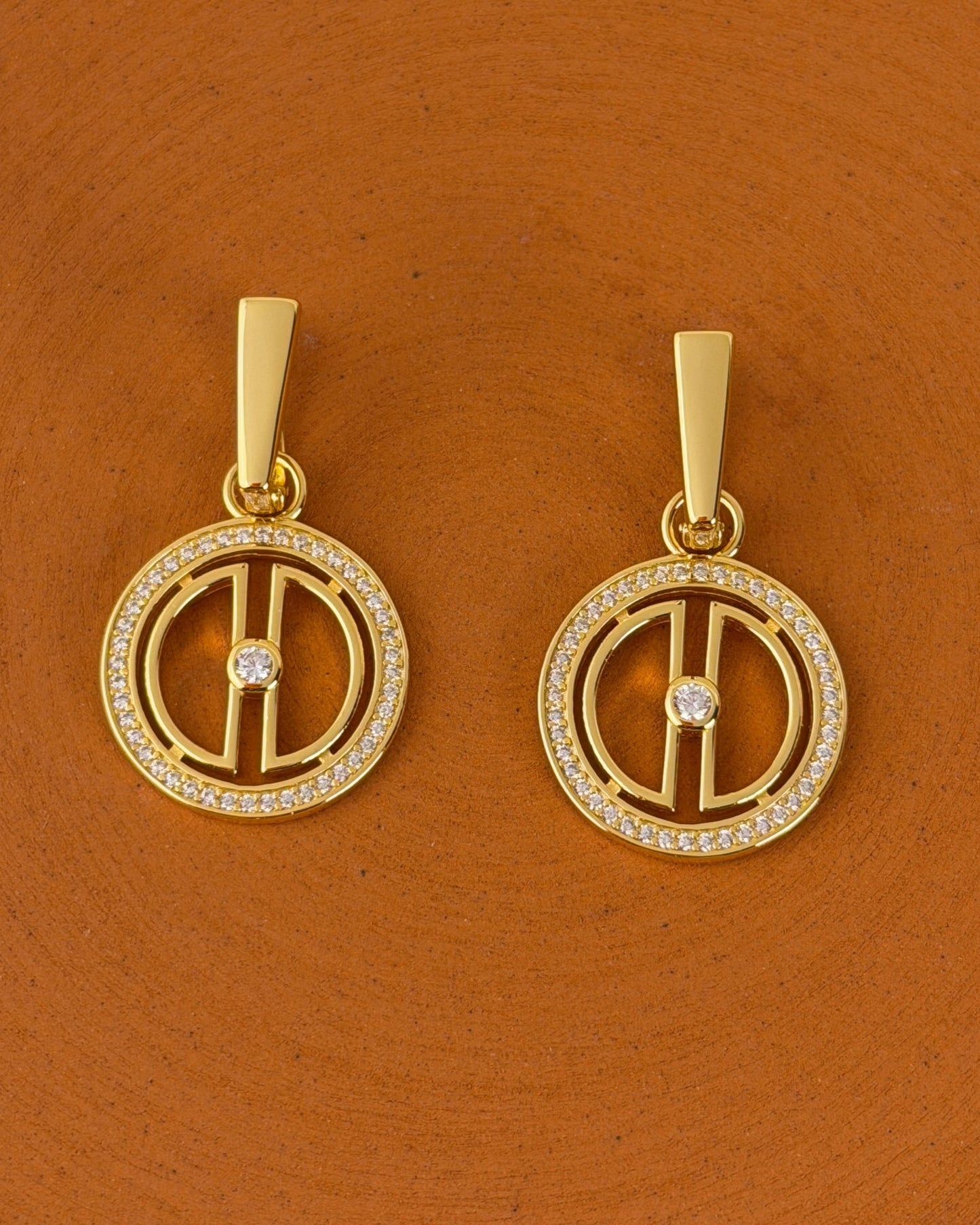 Close-up of 18K gold vermeil moon earrings with sparkling cubic zirconia details styled on a warm terracotta background.