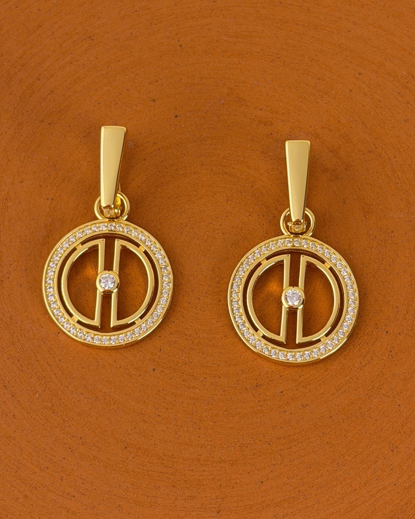 Close-up of 18K gold vermeil moon earrings with sparkling cubic zirconia details styled on a warm terracotta background.