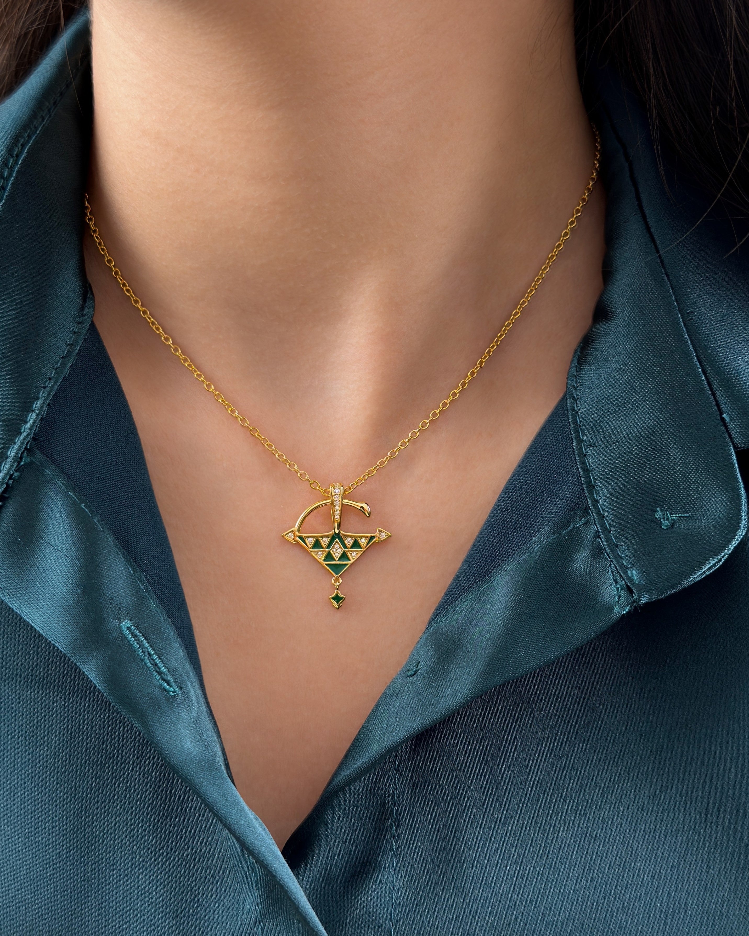 Woman wearing a green enamel Tizerzit necklace in 18k gold vermeil, styled with a deep teal satin shirt for a refined jewelry look.