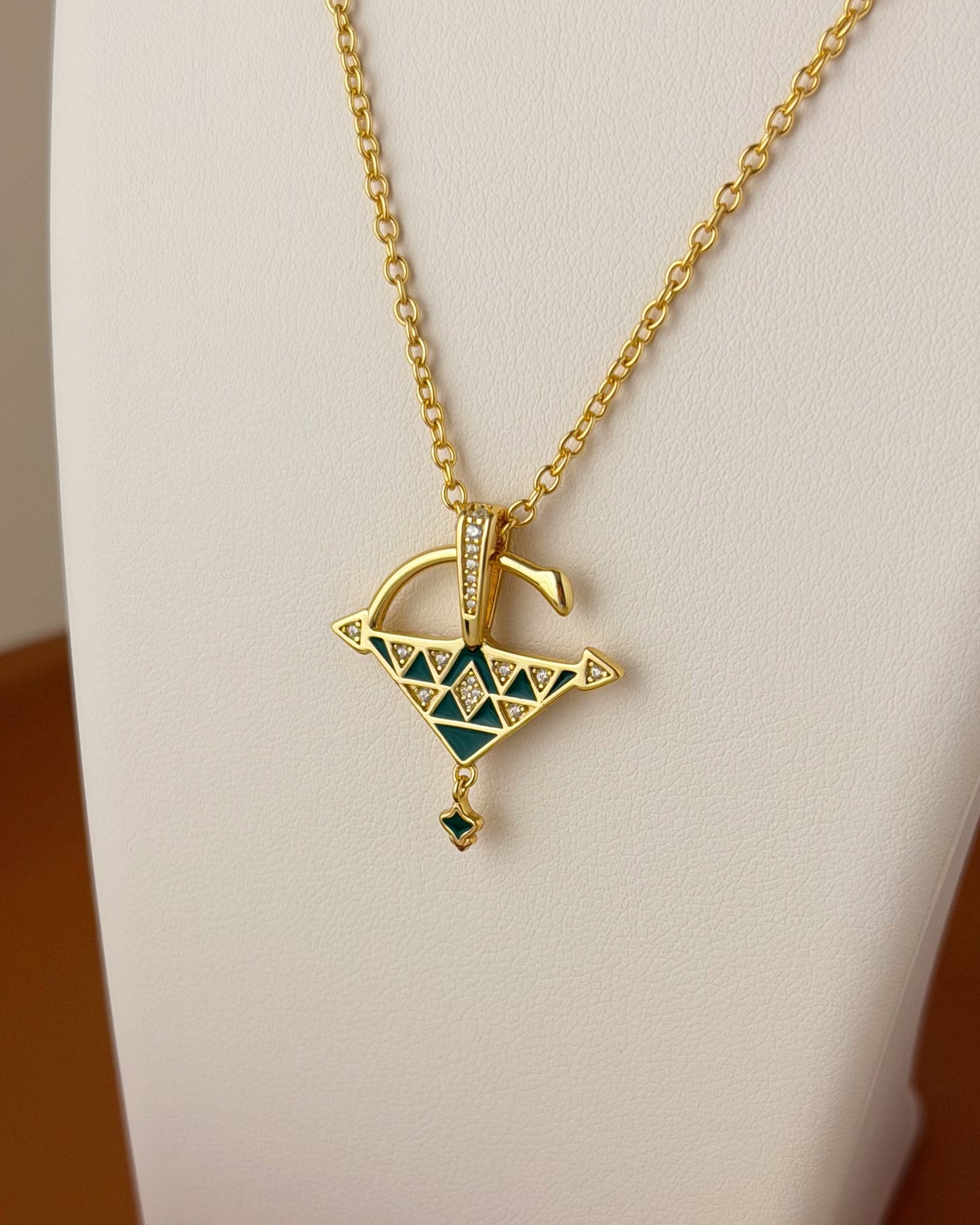 Close-up of a green enamel Tizerzit pendant necklace in 18k gold vermeil over sterling silver, displayed on a white jewelry bust.
