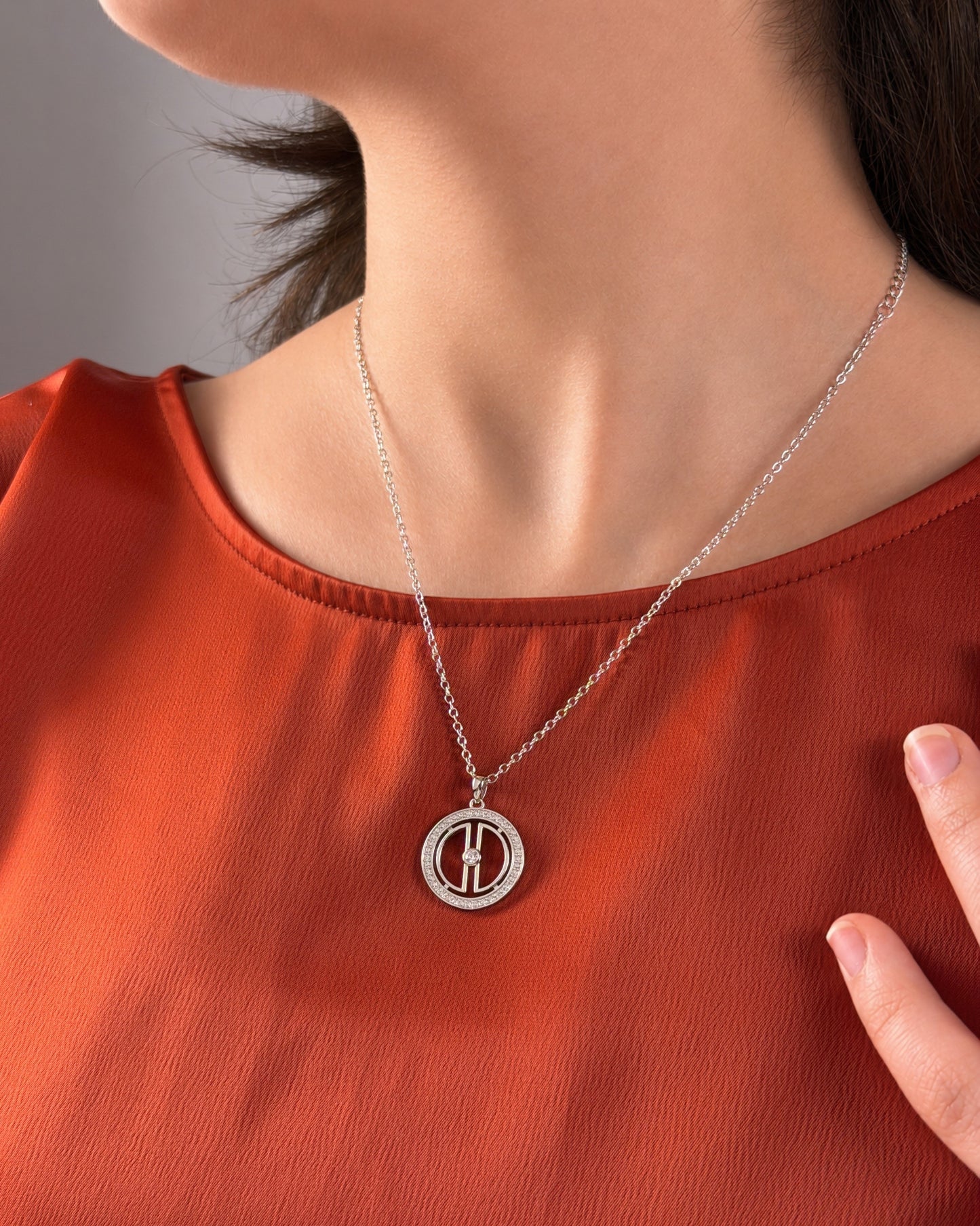 Woman wearing a rhodium-plated silver moon necklace on a terracotta top, showing the pendant size and everyday styling.