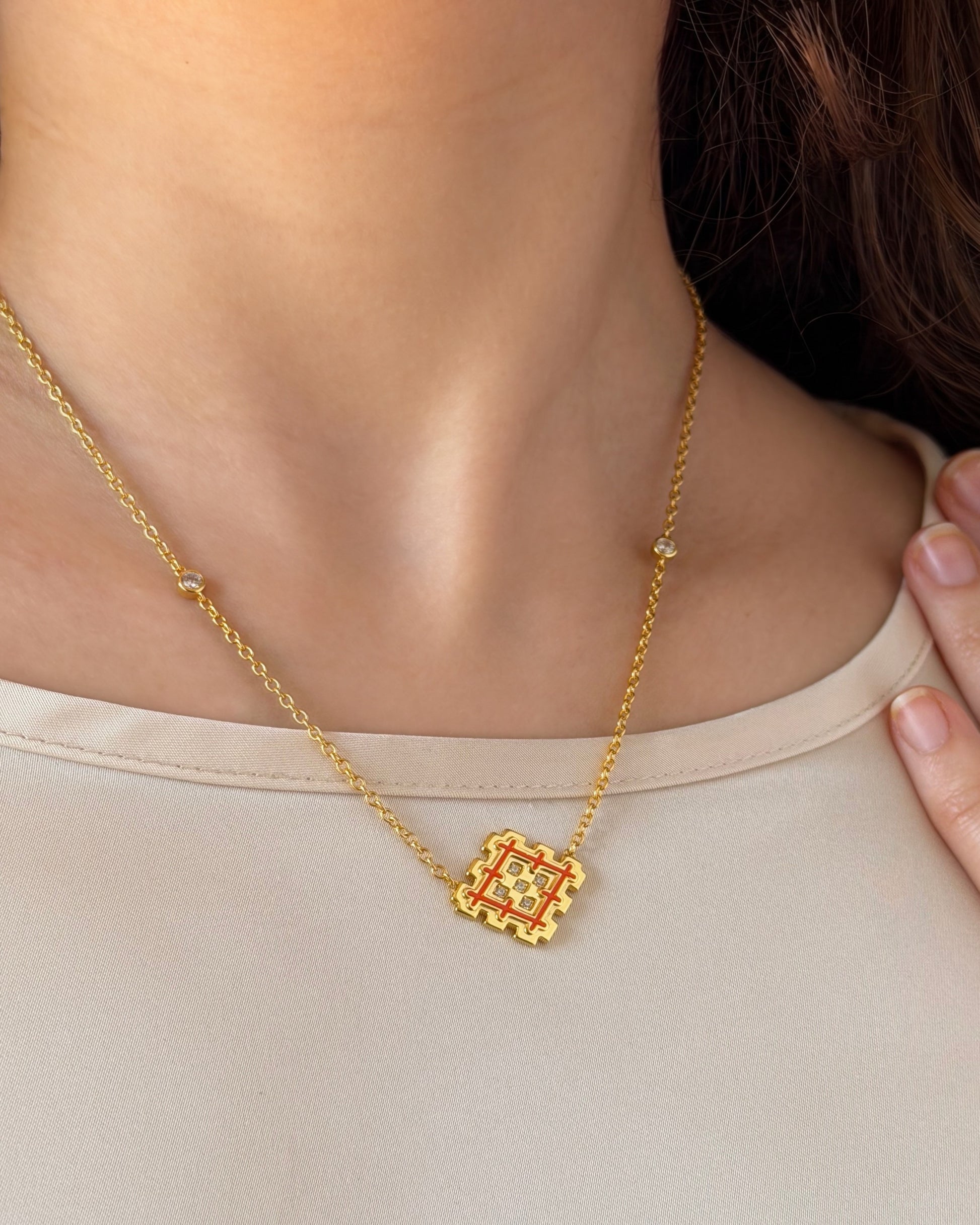 Woman wearing a gold vermeil Lion’s Paw necklace with orange enamel, showing the pendant size and warm everyday styling.