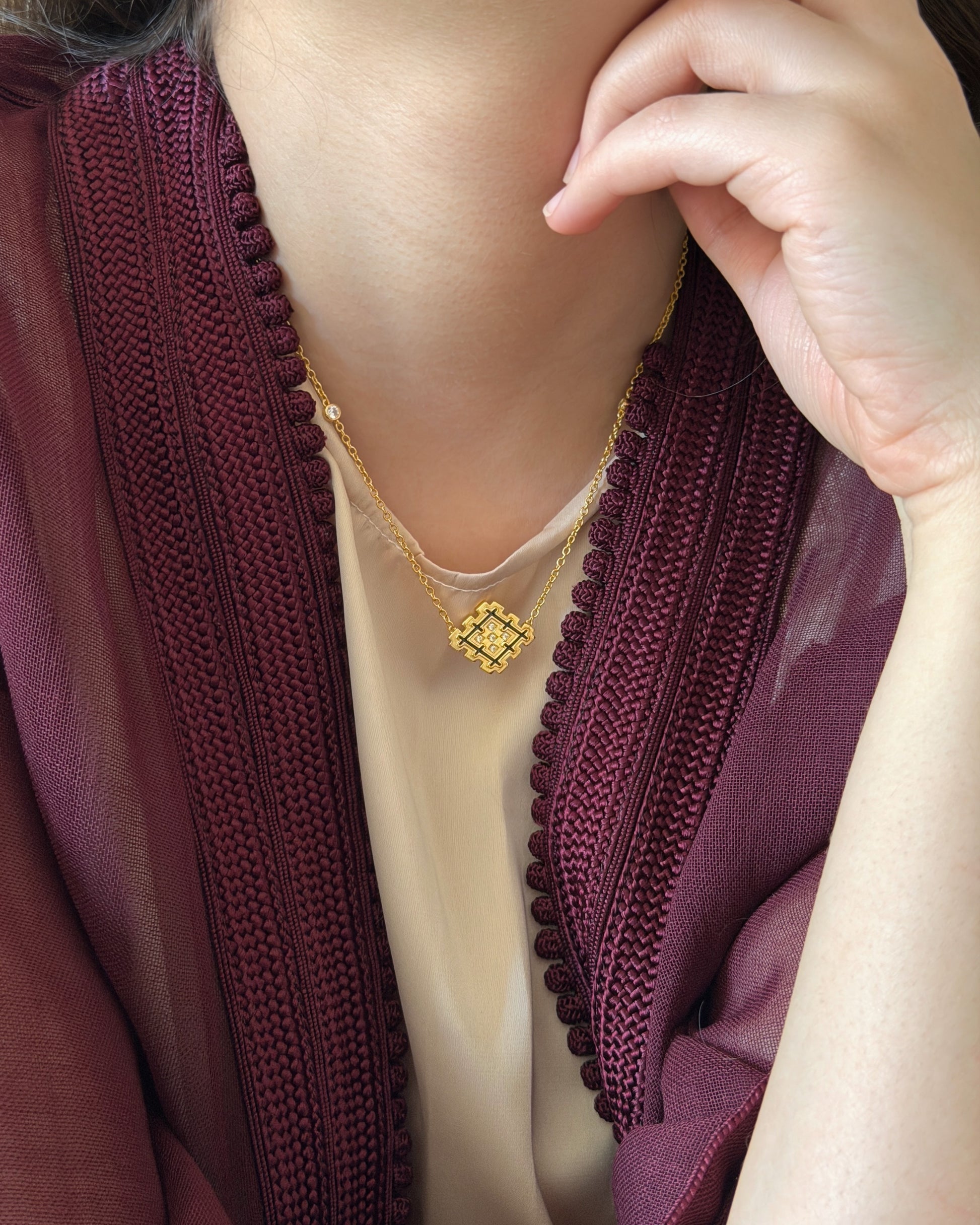 Lifestyle photo of a woman wearing the black enamel Lion’s Paw necklace with a burgundy Moroccan-inspired outfit, highlighting the cultural styling of the piece.
