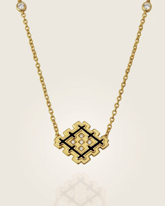 Gold vermeil Lion’s Paw necklace with black enamel and sparkling zirconia details, displayed against a soft neutral background with subtle reflection.