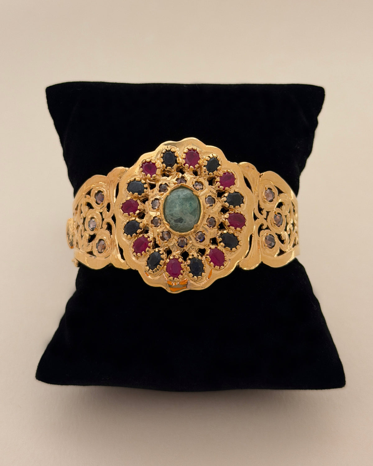 Front view of a Moroccan filigree bracelet in 925 sterling silver with standard gold plating and midnight-blue, red, pink and green stones.